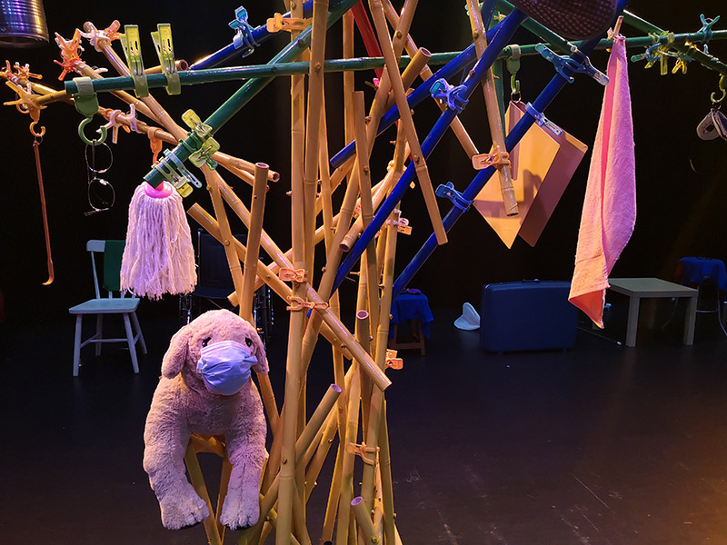 A complex structure made out of several thin, hollow poles. Many laundry clips and household items, such as a mop, towel and plush toy, hang off the structure.
